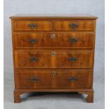 A George III style crossbanded walnut chest of two short over three graduating drawers with brass