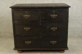 A 20th century black painted pine two short over two long drawers with brass swing handles raised on