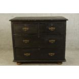 A 20th century black painted pine two short over two long drawers with brass swing handles raised on