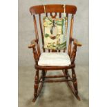 A 20th century mahogany Windsor style open arm splat back rocking chair raised on turned supports