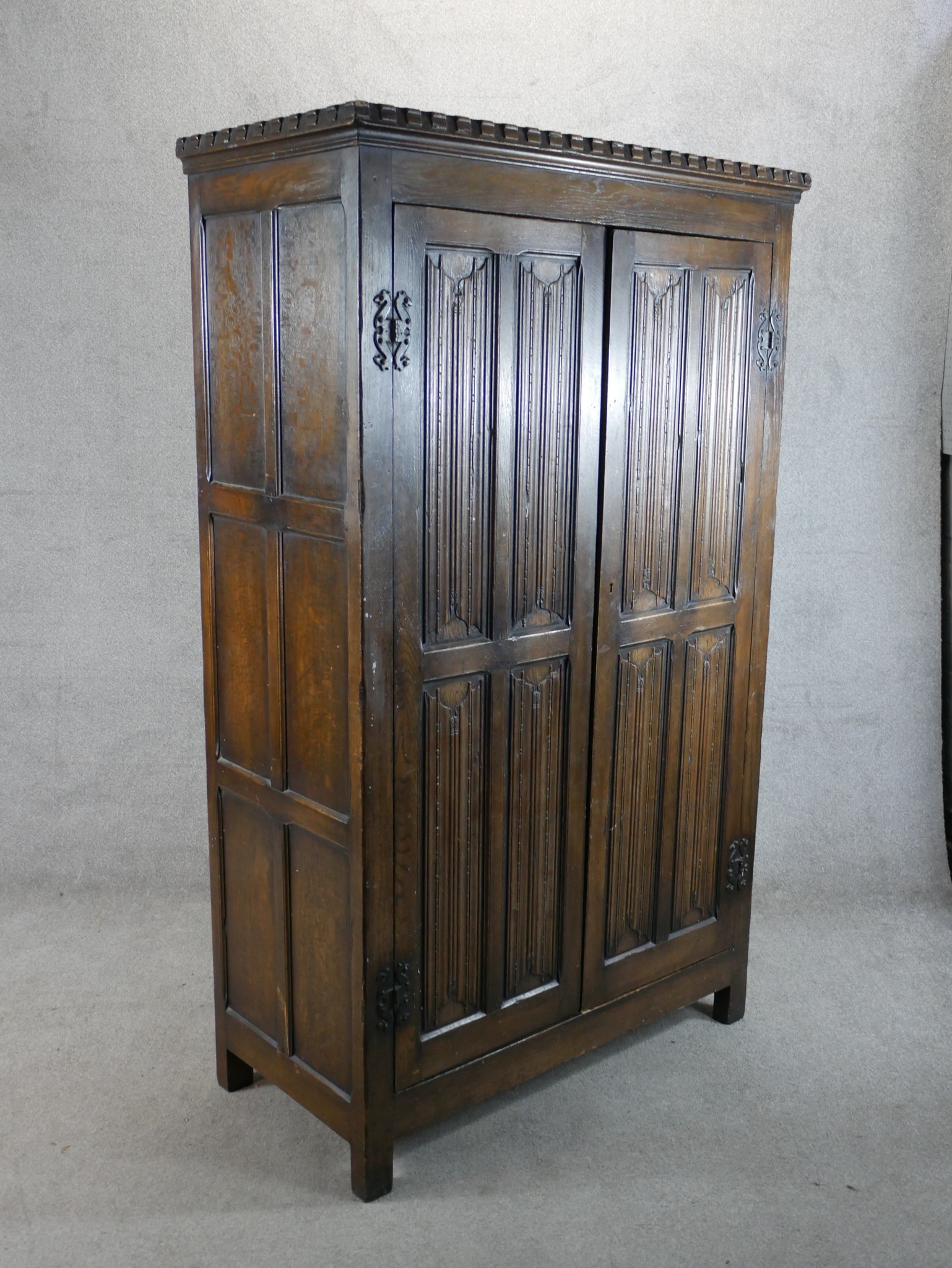 A 20th century stained oak twin door wardrobe with panels of linen fold decoration raised on - Image 3 of 5