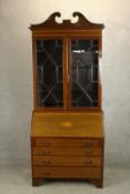 An Edwardian inlaid mahogany bureau bookcase with broken swan neck pediment, the twin doors