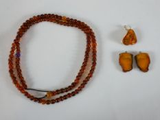 A long string of round Baltic amber beads along three amber slice pendants one with a silver bale.