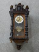 A 19th century mahogany and walnut Vienna style wall clock, with turned finials, the glass door