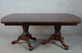 A Victorian style mahogany twin pillar dining table with heavily carved columns each on three