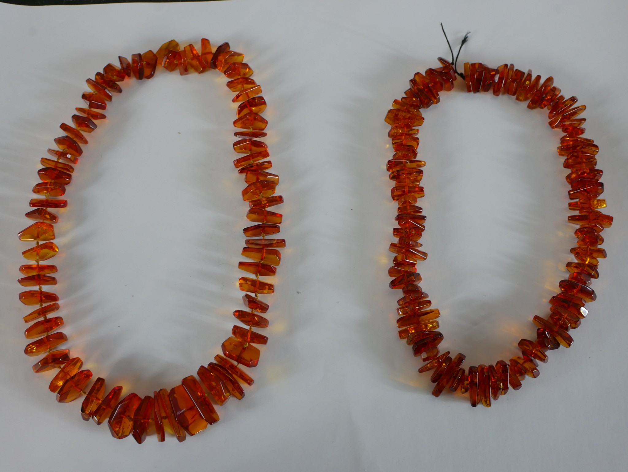 Two strings of polished Baltic amber chips graduating in size. H.56 W.2cm largest