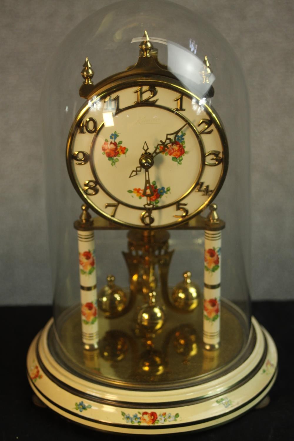 A mid 20th century brass anniversary clock, the white dial painted with floral panel and Arabic