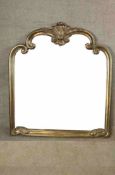 A 20th century gilt framed wall shaped overmantel mirror with carved decoration. H.118 W.120cm.