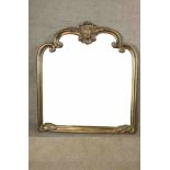 A 20th century gilt framed wall shaped overmantel mirror with carved decoration. H.118 W.120cm.