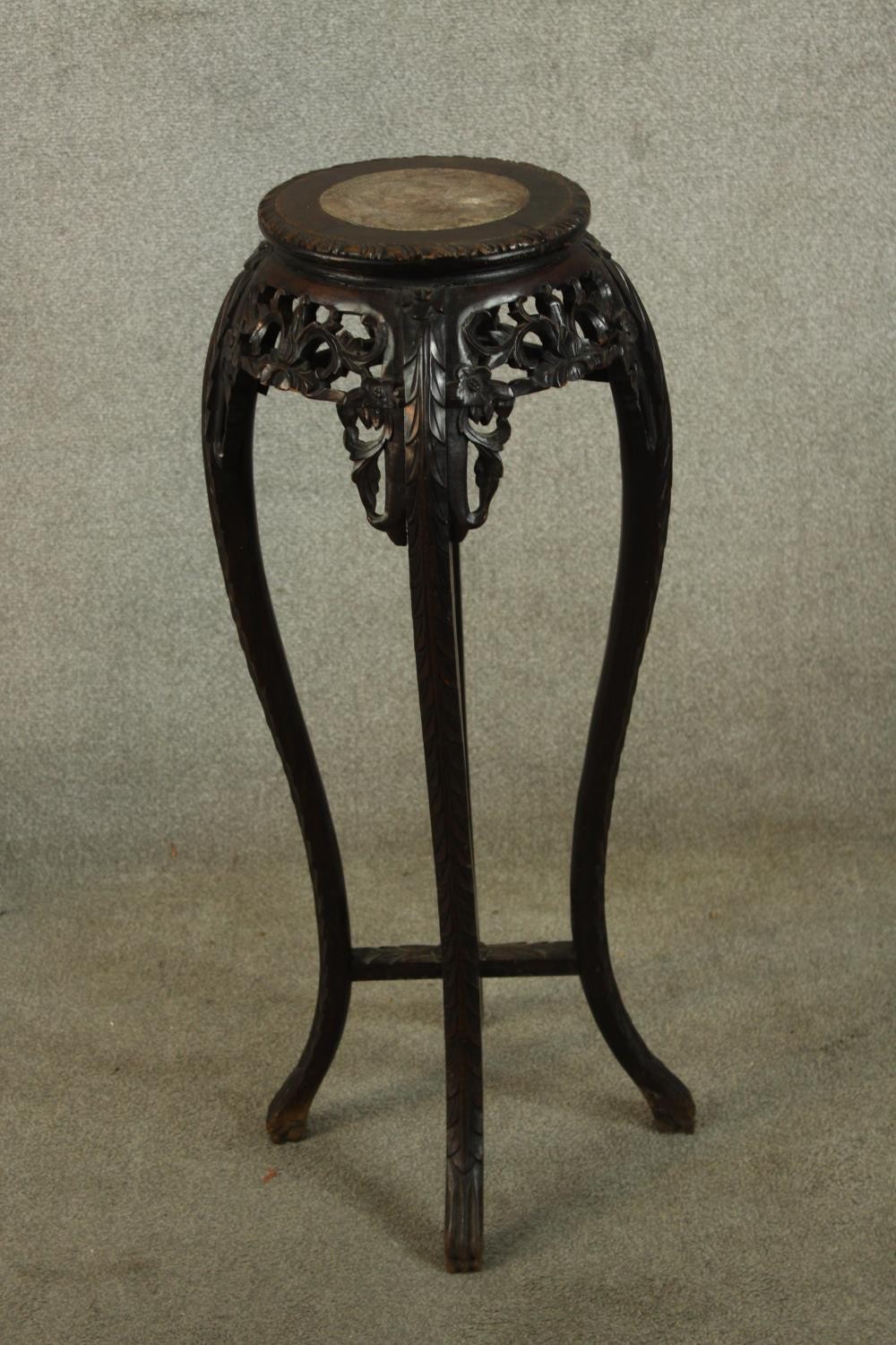 A 19th/early 20th century carved Chinese hardwood and marble plant stand raised on four curved