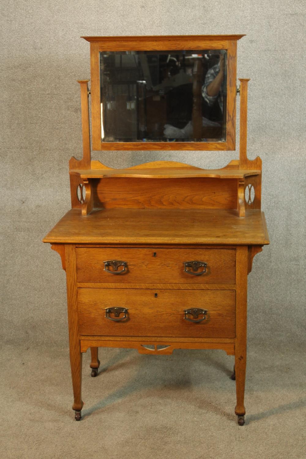 A late 19th/early 20th century mirror back oak two drawer dressing chest raised on turned supports