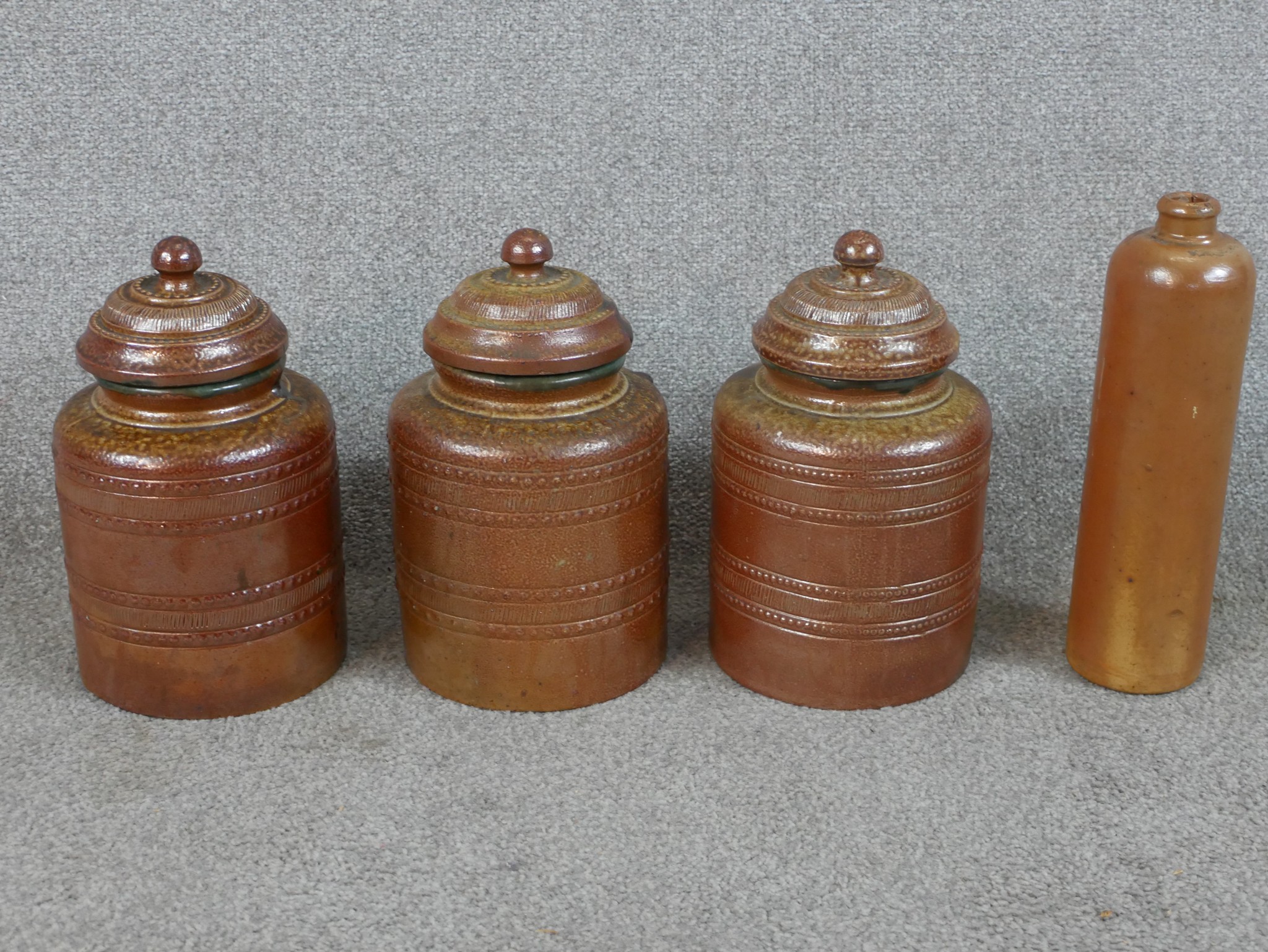 Three 19th century salt glaze Campos Filhos Aveiro pottery lidded storage jars and a similar bottle.