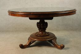 A William IV circular Rosewood tilt top table with carved urn shaped central column raised on four