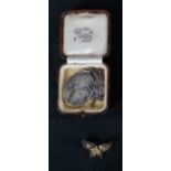A hammered silver oval locket and chain along with a Shakudo ware butterfly brooch with gilded peony