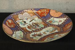 A large late 19th/early 20th century Japanese Imari porcelain charger decorated with figures in a