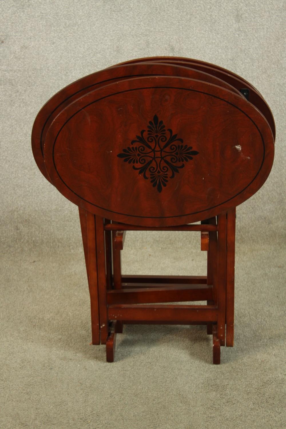 A set of three 20th century mahogany oval topped folding tables with leaf decoration. H.80cm.