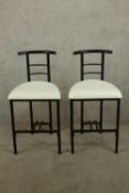 A pair contemporary ebonised bar chairs, possibly after Rodney Kinsman, with cream upholstered seats