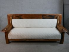 A 20th century tropical hardwood framed settee with cream cotton seat and back cushion. H.85 W.205