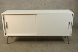 A contemporary white Formica veneered two sliding door cabinet raised on tubular metal supports. H.