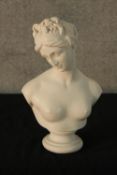 An early 20th century painted porcelain bust of a semi clad classical lady raised on turned socle