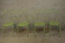 A set of four green painted metal garden chairs with pierced scroll work backs.