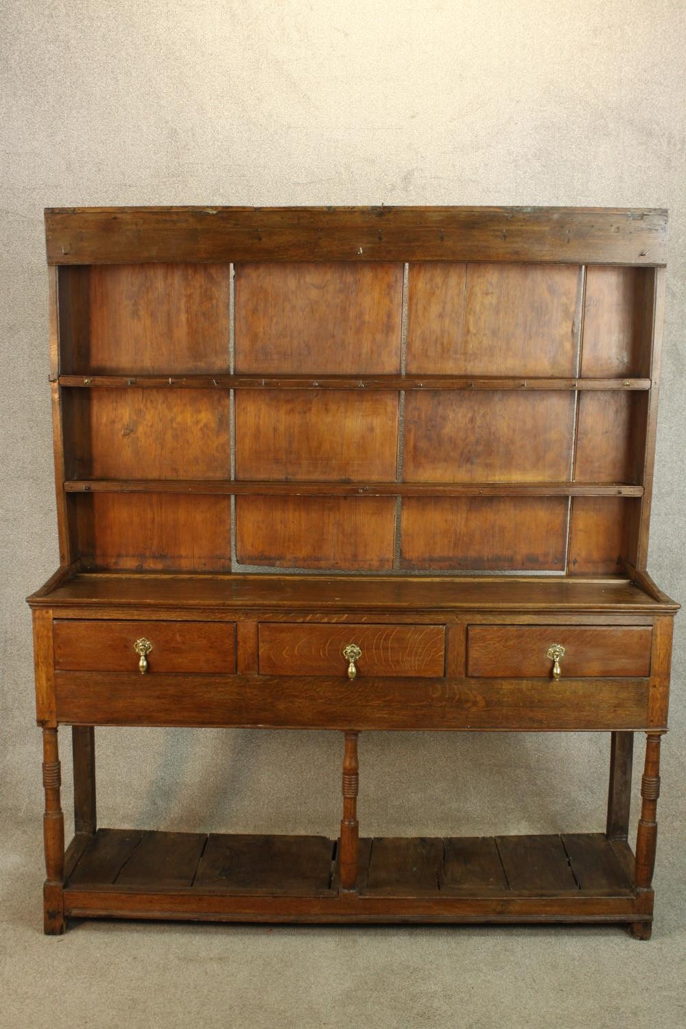 A 19th/early 20th century oak kitchen dresser, with plate rack back standing above three drawers