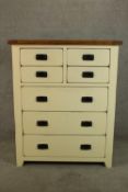A contemporary painted oak chest of four short over three long chest of drawers raised on shaped