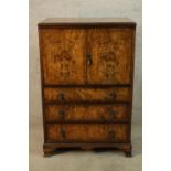 An early 20th century walnut twin door tallboy opening to reveal single shelf above three graduating