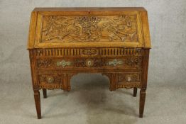 A late 19th/early 20th century carved oak fall front bureau opening to reveal fitted interior with a