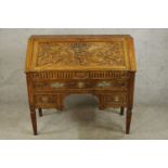 A late 19th/early 20th century carved oak fall front bureau opening to reveal fitted interior with a