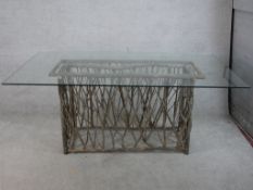A contemporary glass topped table raised on modernist rectangular twig base. H.77 W.180 D.100cm