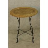 A vintage style wicker topped garden table raised on iron supports with 'X shaped stretcher. H.84