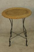 A vintage style wicker topped garden table raised on iron supports with 'X shaped stretcher. H.84