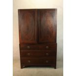 A 19th century mahogany twin door linen press opening to reveal slides standing on two short over