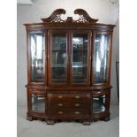 A large 20th century mahogany four glazed door bombe shaped display cabinet raised on three