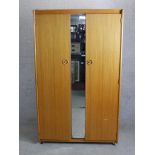 A mid 20th century Schreiber twin door wardrobe with central mirrored panel raised on square