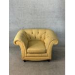 A 19th century button back scroll arm deep seated yellow upholstered armchair raised on turned
