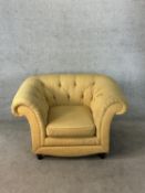 A 19th century button back scroll arm deep seated yellow upholstered armchair raised on turned