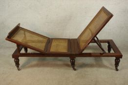 A 19th century mahogany framed and cane adjustable folding day bed raised on turned supports
