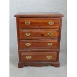 A contemporary Broyhill chest of four long drawers with brass swing handles raised on shaped bracket