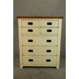 A contemporary painted oak chest of four short over three long chest of drawers raised on shaped