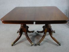 A Regency mahogany twin pedestal extending dining table raised on central turned column each with