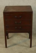 A 19th century mahogany bedside chest of three short drawers with brass swing handles raised on