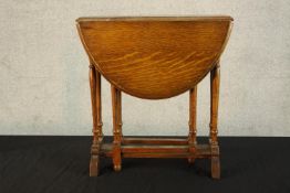 A small early 20th century oak gateleg dropflap Sutherland style occasional table raised on turned