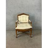 A late 19th century French carved beech framed open arm upholstered button back and cane chair
