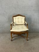 A late 19th century French carved beech framed open arm upholstered button back and cane chair