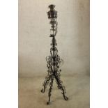 A late 19th/early 20th century painted wrought iron floor standing candle holder raised on four