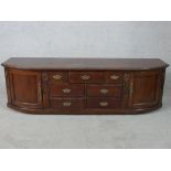 A Victorian style stained teak D shaped sideboard with twin panelled doors, flanked by seven small