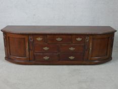 A Victorian style stained teak D shaped sideboard with twin panelled doors, flanked by seven small