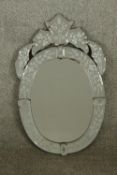 A late 19th/early 20th century Venetian style glass oval wall hanging mirror with incised floral